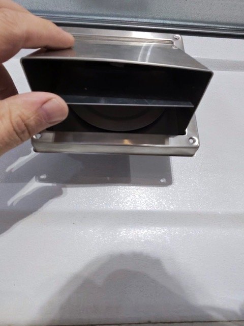 Layer Latch installed on a dryer vent, held open to show the original vent flap underneath